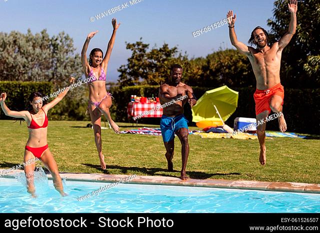 Diverse group of friends having fun and jumping into water at a pool party