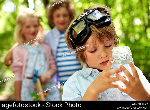 Portrait of boy holding jar in forest