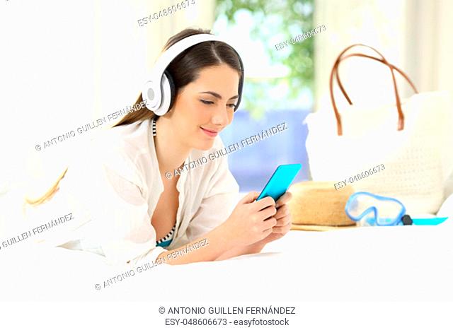 Hotel guest lying on a bed listening to music on summer vacations