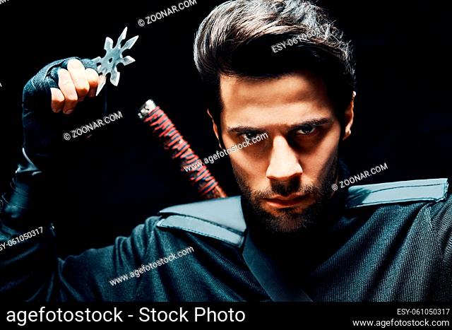 Warrior fighter with a sword and shuriken ready to stab enemy over black background. japanese fighter concept