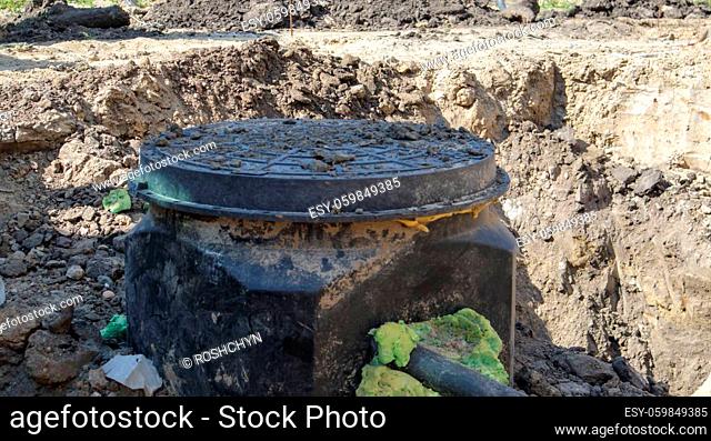 Installation, assembly of a new plastic sewer hatch into the ground. Construction of sewerage networks. Installation of an underground sewerage tank