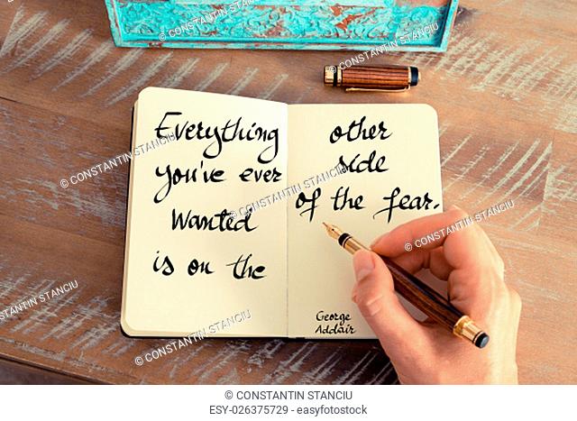 Retro effect and toned image of a woman hand writing on a notebook. Handwritten quote Everything you’ve ever wanted is on the other side of fear – George Addair...