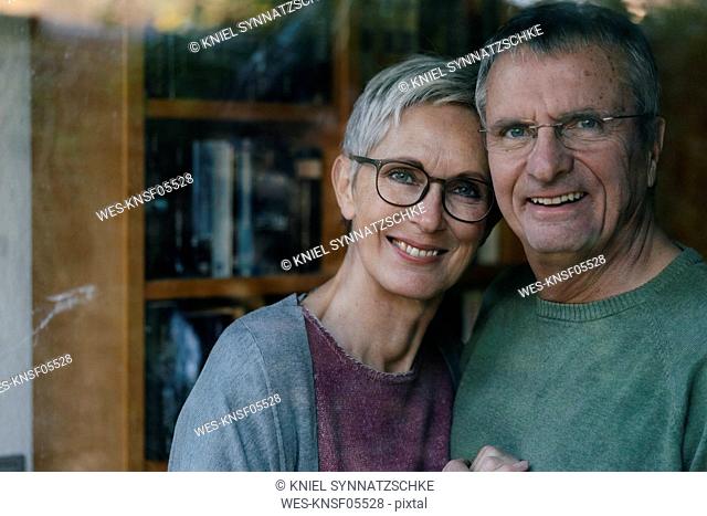 Portrait of happy senior couple behind windowpane
