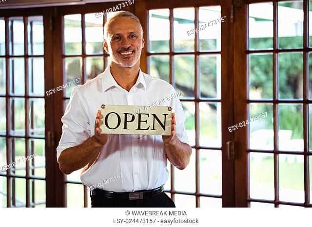 Smiling man holding a sign with open