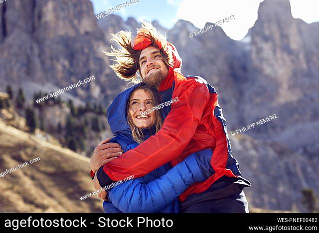Happy young couple hugging in windy mountains