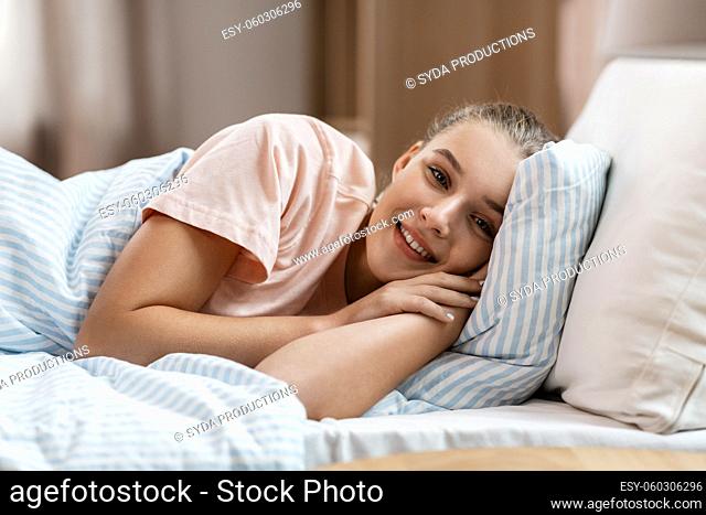 happy smiling awake girl lying in bed at home