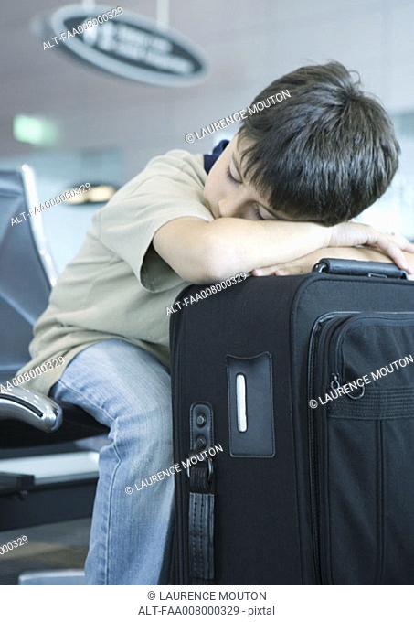 Boy resting head on suitcase, sleeping