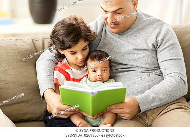 happy father with sons reading book at home