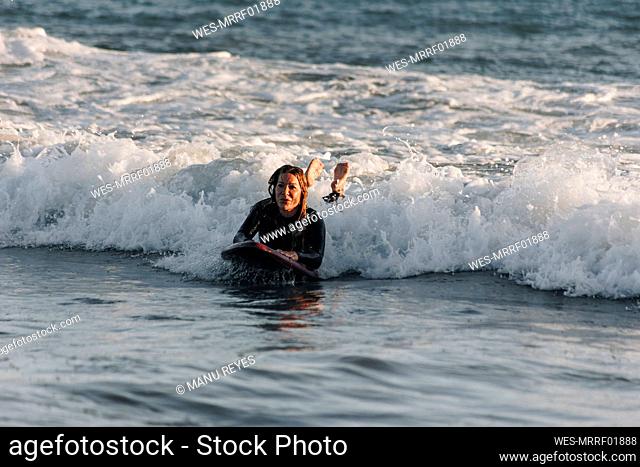 Woman surfing in sea lying on surfboard, Gran Canaria, Canary Islands