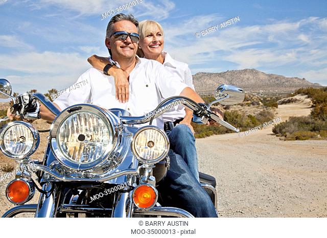 Senior couple on desert road sitting on motorcycle