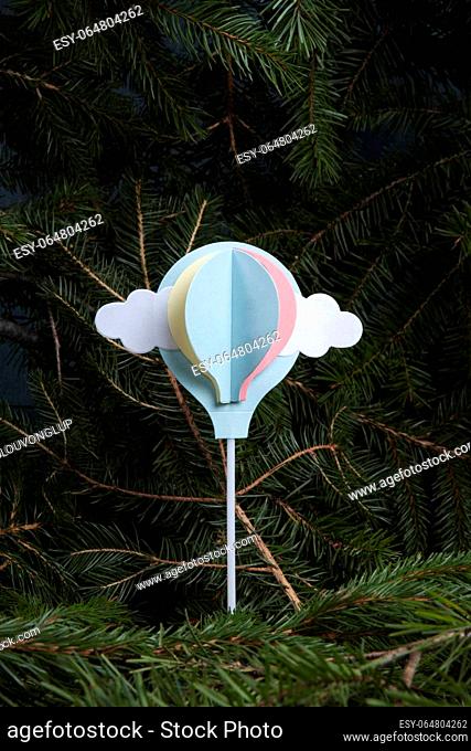 a paper hot-air balloon, initially a cake decoration, flying up from a fir-tree forest. A poetic illustration of freedom