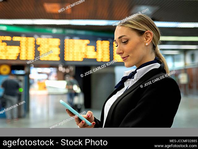 Young air stewardess using smart phone at airport