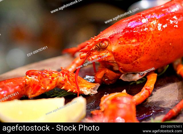 The whole lobster steamed, served with lemon on wooden plate. Close up