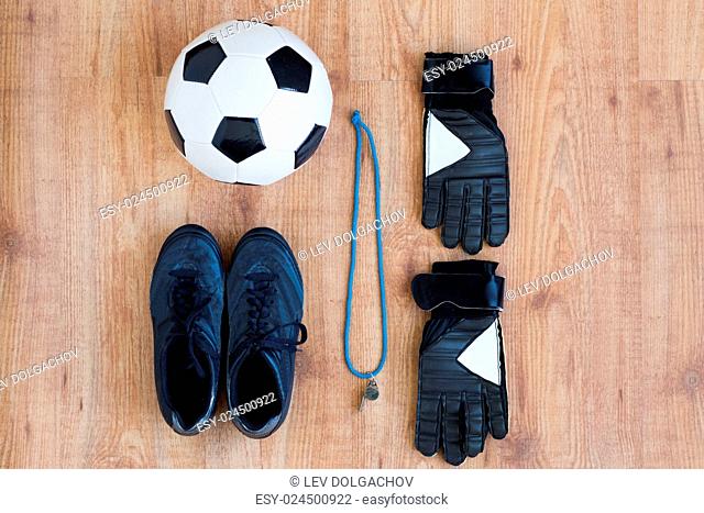 sport, football and sports equipment concept - close up of soccer ball, boots, whistle and gloves on wooden background
