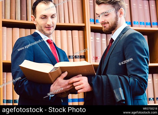 Two lawyers in the law firm discussing cases and precedents in front of bookshelf