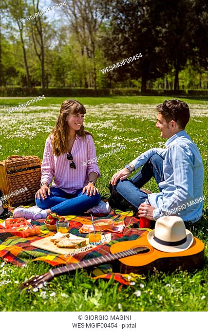 Young couple having a picnic with healthy food in a park