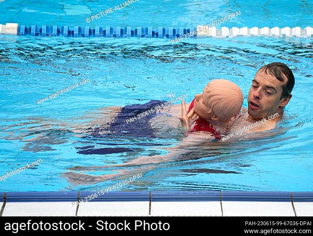 14 June 2023, Berlin: 34-year-old Fabian demonstrates the procedure for rescuing a casualty on a mannequin while pre-swimming potential lifeguards at the...