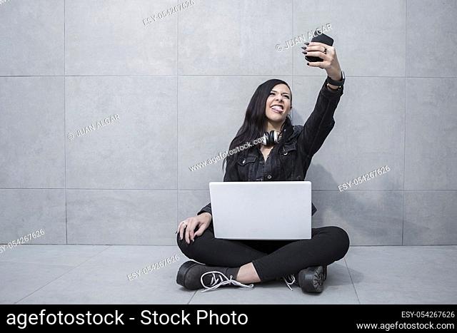 Casual woman grimacing while taking selfie and sitting with laptop
