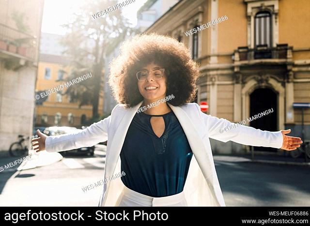 Businesswoman with arms outstretched walking in city