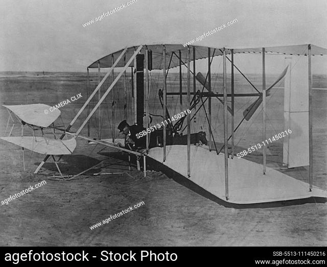 Wright Brothers 1903 Aeroplane (Kitty Hawk) on ground. Probably Wilbur Wright lying prone at controls. Evidence indicates photo was taken after first flight...