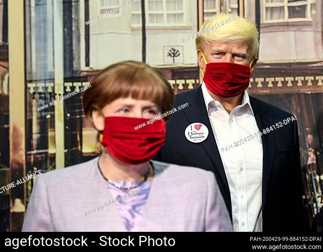 29 April 2020, Berlin: The figures of Federal Chancellor Angela Merkel and US President Donald Trump in Madame Tussauds waxworks cabinet wear a mouth and nose...