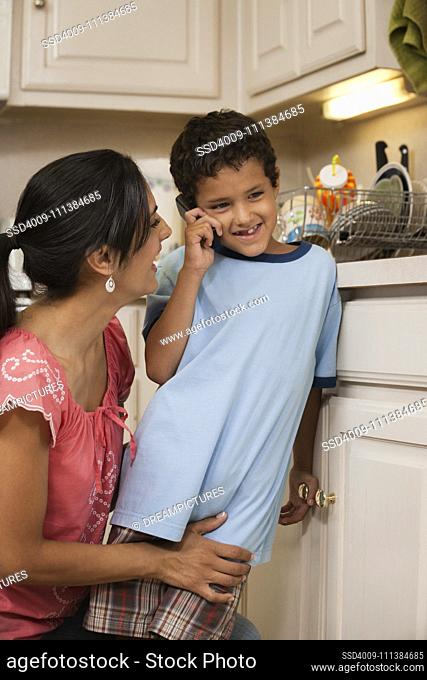 Hispanic mother helping son talk on cell phone