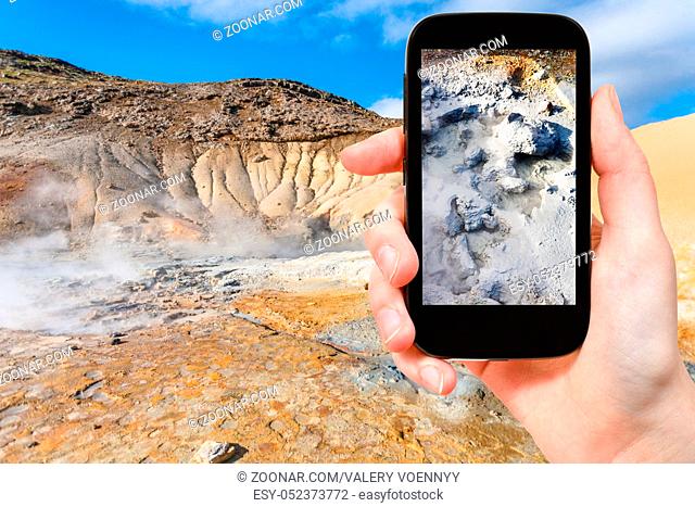 travel concept - tourist photographs mud acidic geyser in geothermal Krysuvik area on Southern Peninsula (Reykjanesskagi
