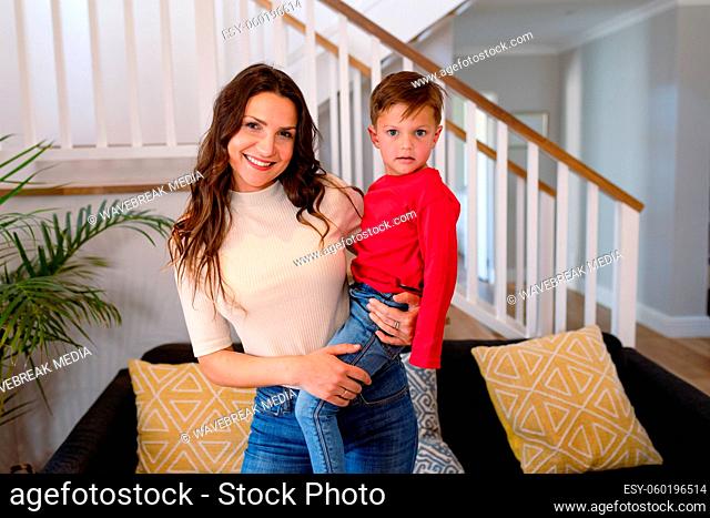 Happy caucasian mother holding son and looking at camera