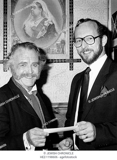 Sir John Mills (1908- ), British actor. Receiving a cheque from Mr Paul Kustow, the chairman of the Northwood and Pinner Liberal Synagogue's functions committee