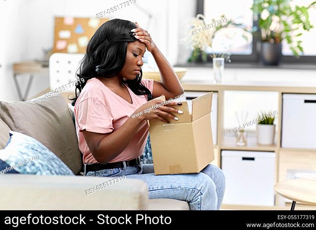sad african american woman with parcel box at home