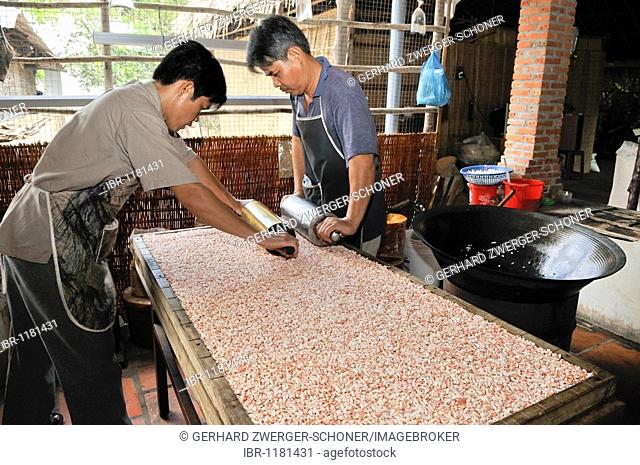 Men rolling flat puffed rice dough, preparation of sweets, confectionery factory, Vinh Long, Mekong Delta, Vietnam, Southeast Asia