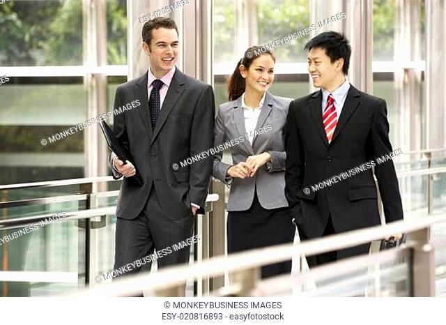 Three Business Colleagues Having Discussion Whilst Walking Outside Office