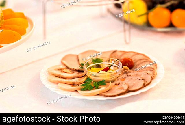 platter of sliced ham, salami and cured meat with vegetable decoration on festive table