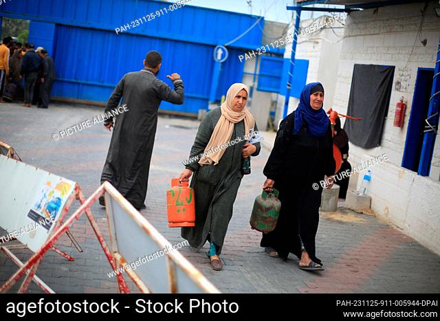 25 November 2023, Palestinian Territories, Khan Yunis: Palestinians carry their liquid gas cylinders after refilling them