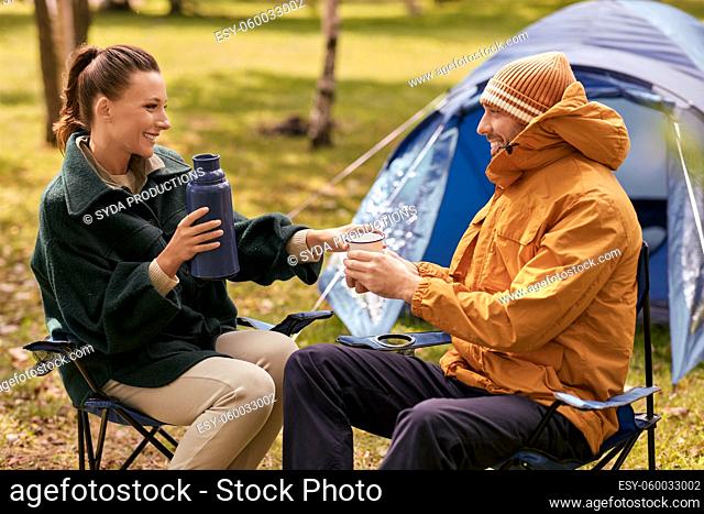 couple with thermos drinking tea at tent camp