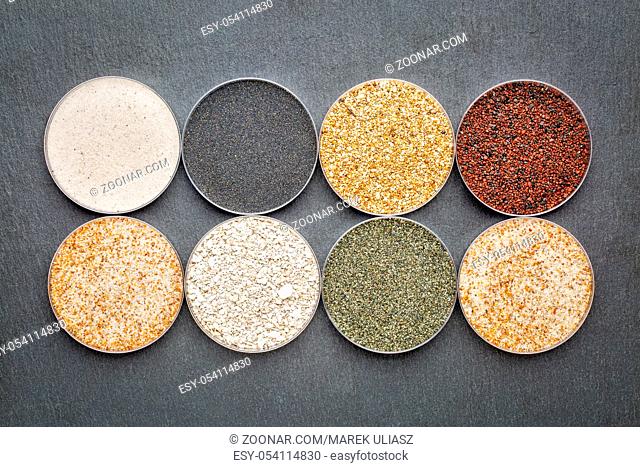 sand samples from beaches in Florida, California and Hawaii - top view of round Petri dishes against slate stone