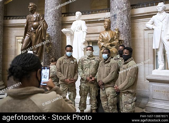 Members of the National Guard take photos next to the statue of Rosa Parks in Statuary Hall of the U.S. Capitol, as the House of Representatives vote on H