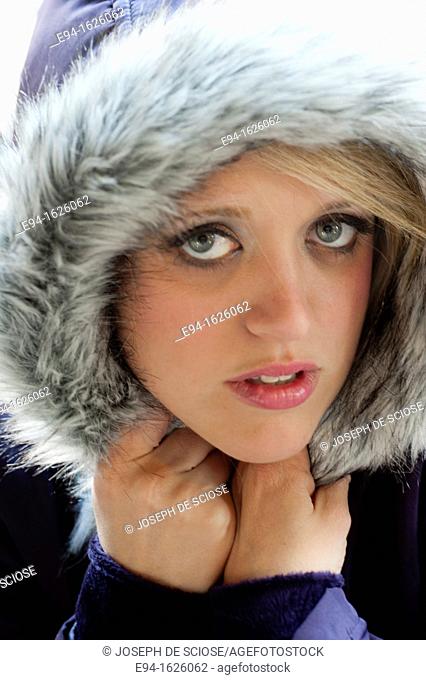 Close in shot of a 31 year old blond woman with a serious expression, eyes to camera  wearing a hooded coat