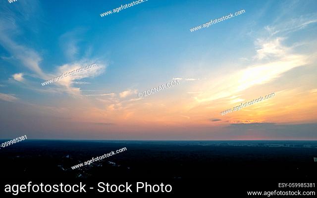 Colorful sky background sunset, illuminated pink-orange dramatic clouds, aerial photography, far horizon, setting sun. Ideal for sky replacement postproces