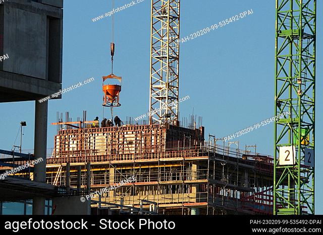 06 February 2023, Hamburg: Workers are busy filling concrete on the top floor of the construction site of a high-rise building in Hafencity