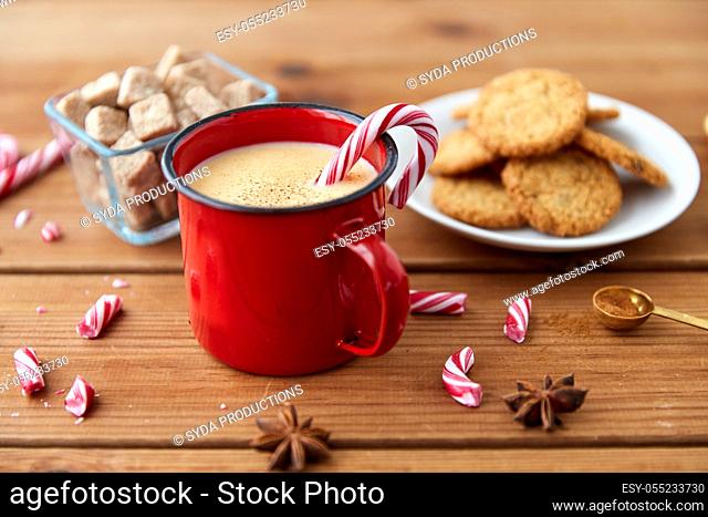cup of eggnog with candy cane, cookies and anise