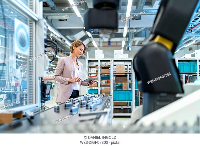 Businesswoman with tablet in a modern factory hall