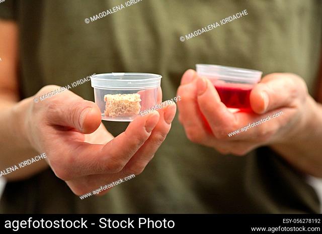 Woman Hands Takes Communion In One Time Use Containers To Protect From The Virus