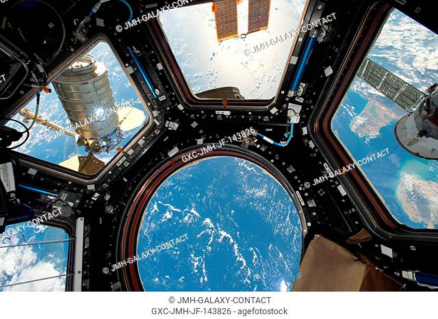 Orbital ATK's Cygnus cargo craft (left) is seen from the Cupola module windows aboard the International Space Station. The main robotic work station for...