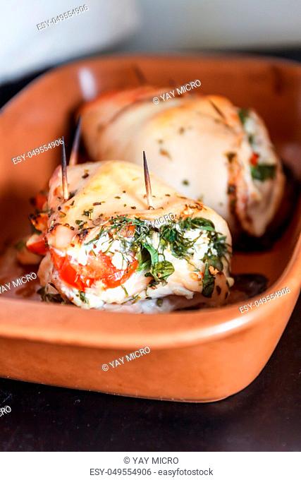 Baked poultry fillet stuffed with soft cheese, tomatoes and herbs in a ceramic baking dish. The concept of the proper beneficial health food, diet
