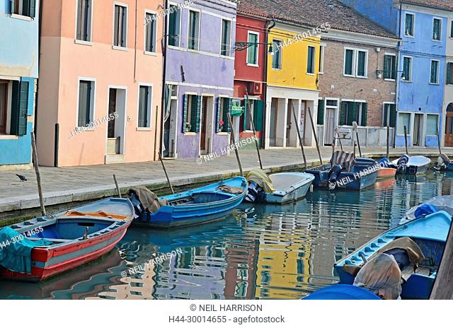 Boats in a canal lined with colorful houses on the pretty little island of Burano in the Venice Lagoon