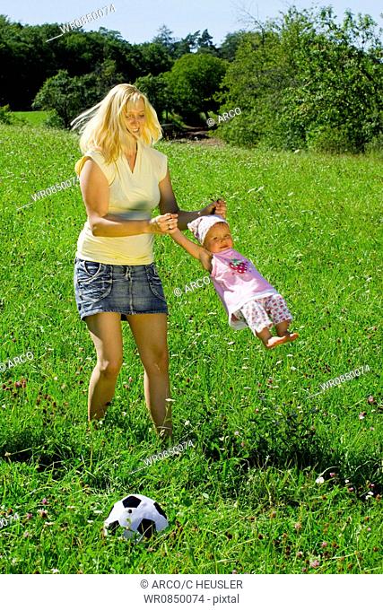 Young mother playing with daughter, flying in circles