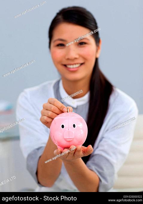 Young ethnic businesswoman saving money in a piggybank