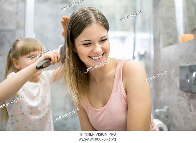 Little girl brushing her mother's hair