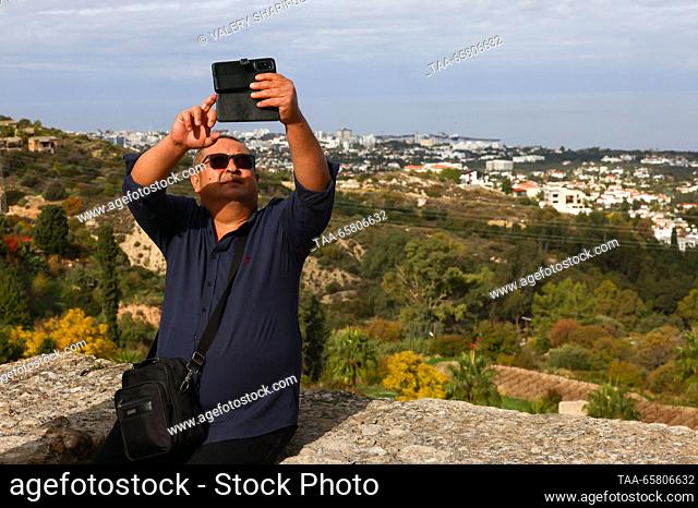 CYPRUS, KYRENIA - DECEMBER 15, 2023: A man takes a photograph of a panoramic view of the town. The Turkish Republic of Northern Cyprus is a de facto state...